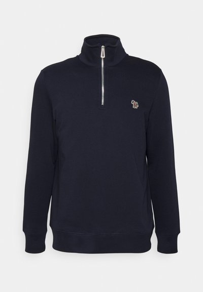 Námornícky modrá mikina na zips s vysokým golierom, dlhými rukávmi a malou vyšitou logom na hrudi. Vyrobená z jemného materiálu.