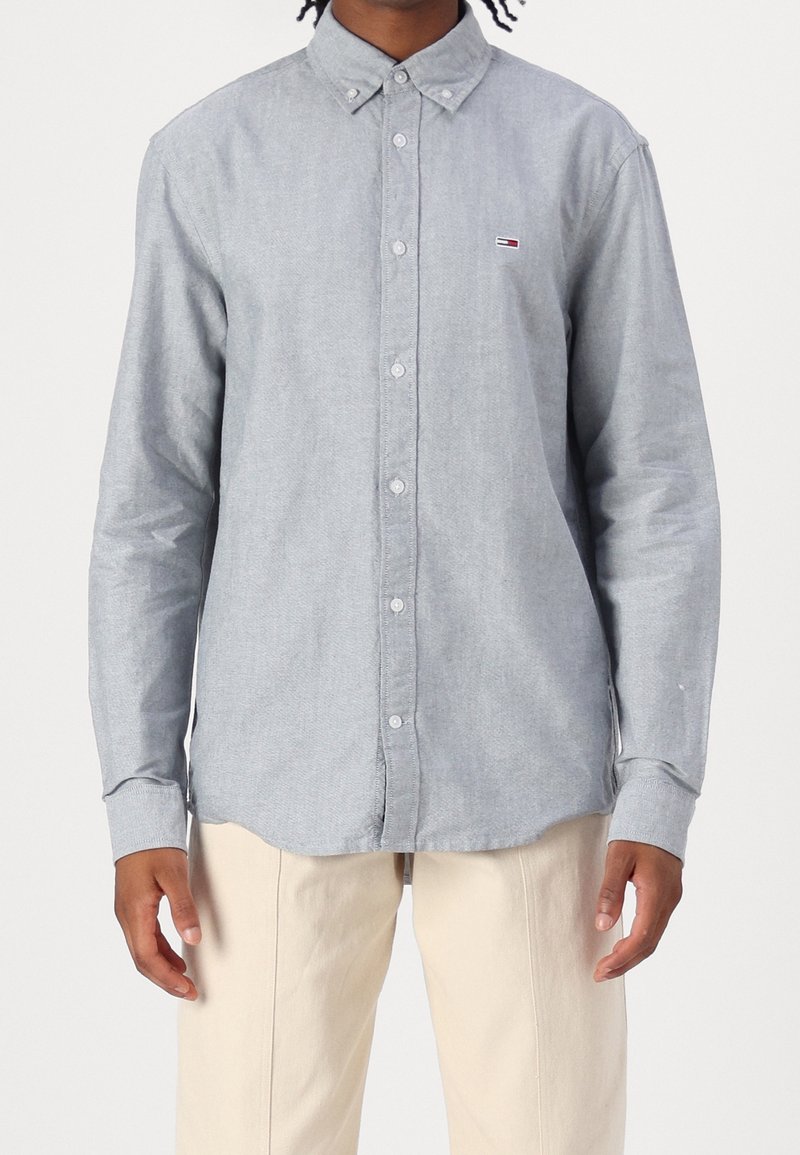 Ljust grå långärmad skjorta med knappar i mjukt tyg, med en button-down krage och en liten logotyp på bröstet.