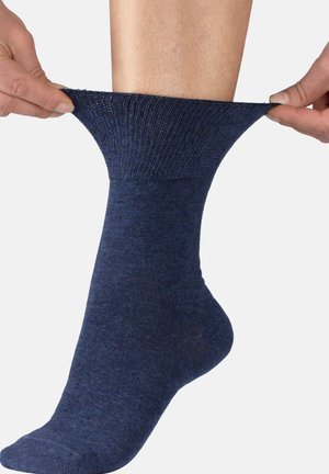 Navy blue sock, ribbed texture at the cuff, smooth body, stretching over an ankle. Material appears soft and elastic for comfort.