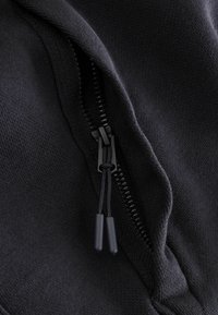 Mustast dressikangast pusa nähtava tõmblukuga, sileda tekstuuri ja musta tõmbluku tõmbajaga. Õmbluse ääres detailne õmblus.