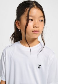 Vit kortärmad skjorta med rund halsringning och en liten svart logga på vänster sida. Slät tyg med avslappnad passform.