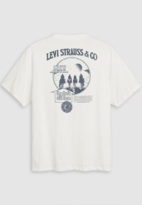 Hvid bomulds t-shirt med et blåt grafisk design, der indeholder tekst og en illustration af tre ryttere. Korte ærmer og afslappet pasform.
