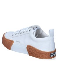 Scarpe da ginnastica bianche in tela con suola in gomma marrone texture, occhielli in argento e un logo sul tallone. Design semplice con punta tonda.
