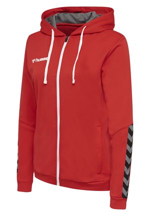 Röd hoodie-jacka med vit dragkedja och snören. Har texturerad tyg och svarta chevron-mönstrade detaljer på ärmarna.