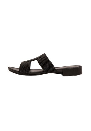 Sandalia negra deslizable con un diseño de tira de tela trenzada, punta abierta, suela plana y detalles mínimos. El zapato tiene una superficie texturizada.