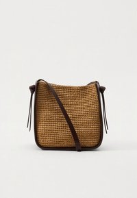 Brown woven bag with a textured surface, featuring a rectangular shape and a leather strap. The design includes tied accents on the sides.