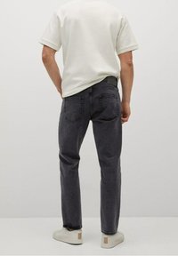 Harmaat farkut suoralla leikkauksella, joissa on klassinen viiden taskun muotoilu ja minimalistiset ompeleet. Yhdistetty valkoiseen T-paitaan ja vaaleisiin kenkiin.