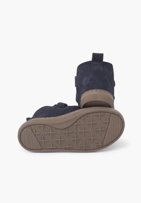 Granatowe zamszowe botki za kostkę z elastyczną brązową gumową podeszwą z wzorzystym bieżnikiem oraz pętlą ułatwiającą zakładanie.