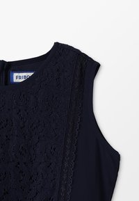 Námořnická modrá blůza s krajkovými detaily na jedné straně, hladkým povrchem a kulatým výstřihem. Štítek nese nápis "FRIBO."