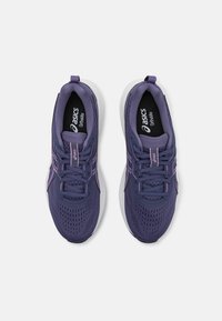Violet sportiniai bateliai su tinklo viršumi, balta padais ir violetiniais akcentais. Yra raištelių uždarymas ir prekės ženklas ant liežuvėlio bei vidpadžio.
