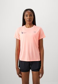T-shirt de sport à manches courtes rose clair avec une texture en maille, arborant le logo New Balance et la marque du marathon de New York TCS. Shorts noirs.