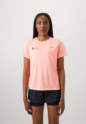 T-shirt de sport à manches courtes rose clair avec une texture en maille, arborant le logo New Balance et la marque du marathon de New York TCS. Shorts noirs.