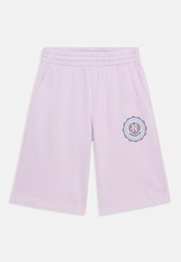 Lyse lilla shorts laget av mykt stoff, med elastisk midjebånd og sidelommer. En rund logo med blå og brun design er på venstre bein.