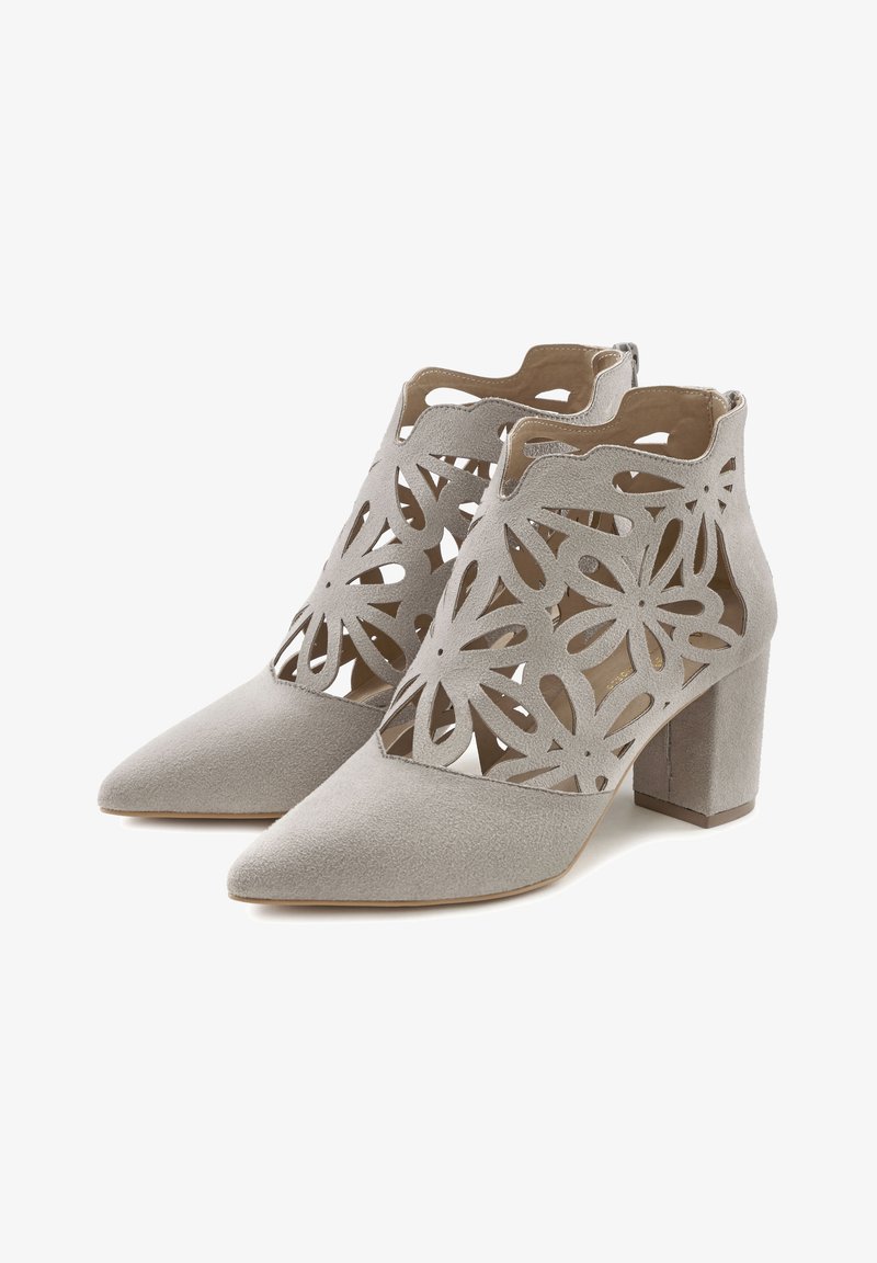 Paire de bottines en daim gris clair avec bouts pointus, talons épais et motifs floraux découpés sur la partie supérieure.