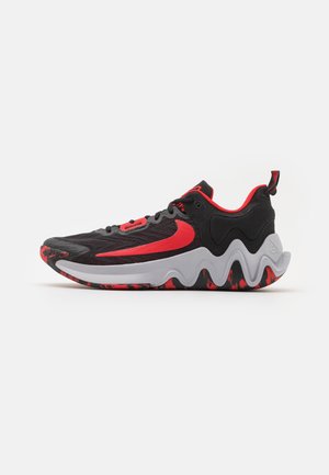 Chaussure de sport noire et rouge avec un grand logo swoosh rouge, semelle intermédiaire blanche ondulée, et semelle extérieure rouge et noire à motif.