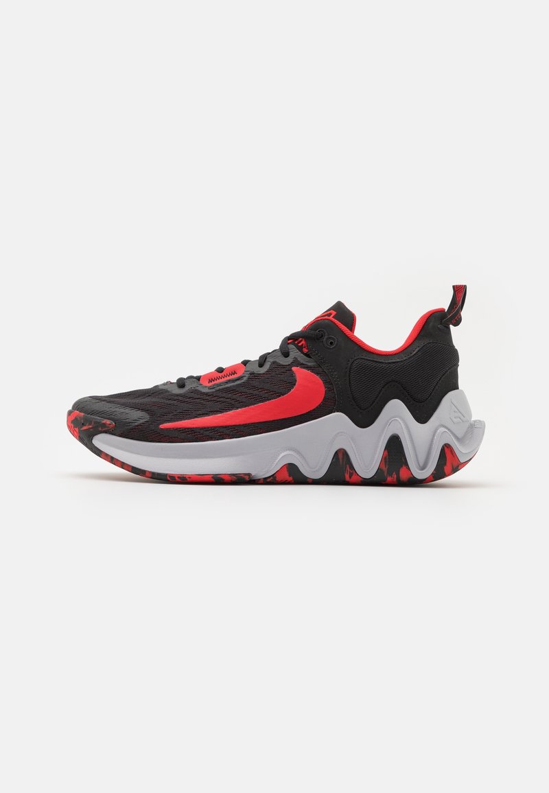 Chaussure de sport noire et rouge avec un grand logo swoosh rouge, semelle intermédiaire blanche ondulée, et semelle extérieure rouge et noire à motif.