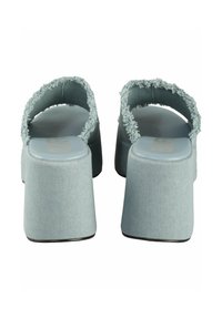 Sandales à plateforme en tissu bleu clair texturé, avec des brides à bord effiloché et un talon rectangulaire épais. Semelle intérieure lisse.