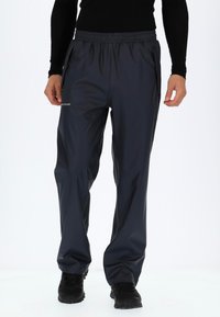 Waterbestendige, donkergrijze trainingsbroek met een elastische tailleband, zijzakken en een gladde textuur. Inclusief subtiele branding op het been.