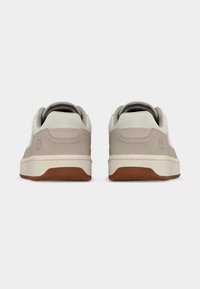 Αθλητικά παπούτσια με λείο ανώτερο μέρος σε κρεμ και ανοιχτό γκρι, σουέντ λεπτομέρειες και καφέ λαστιχένια σόλα. Διαθέτουν επενδεδυμένο κολάρο και λεπτομέρεια με λογότυπο.