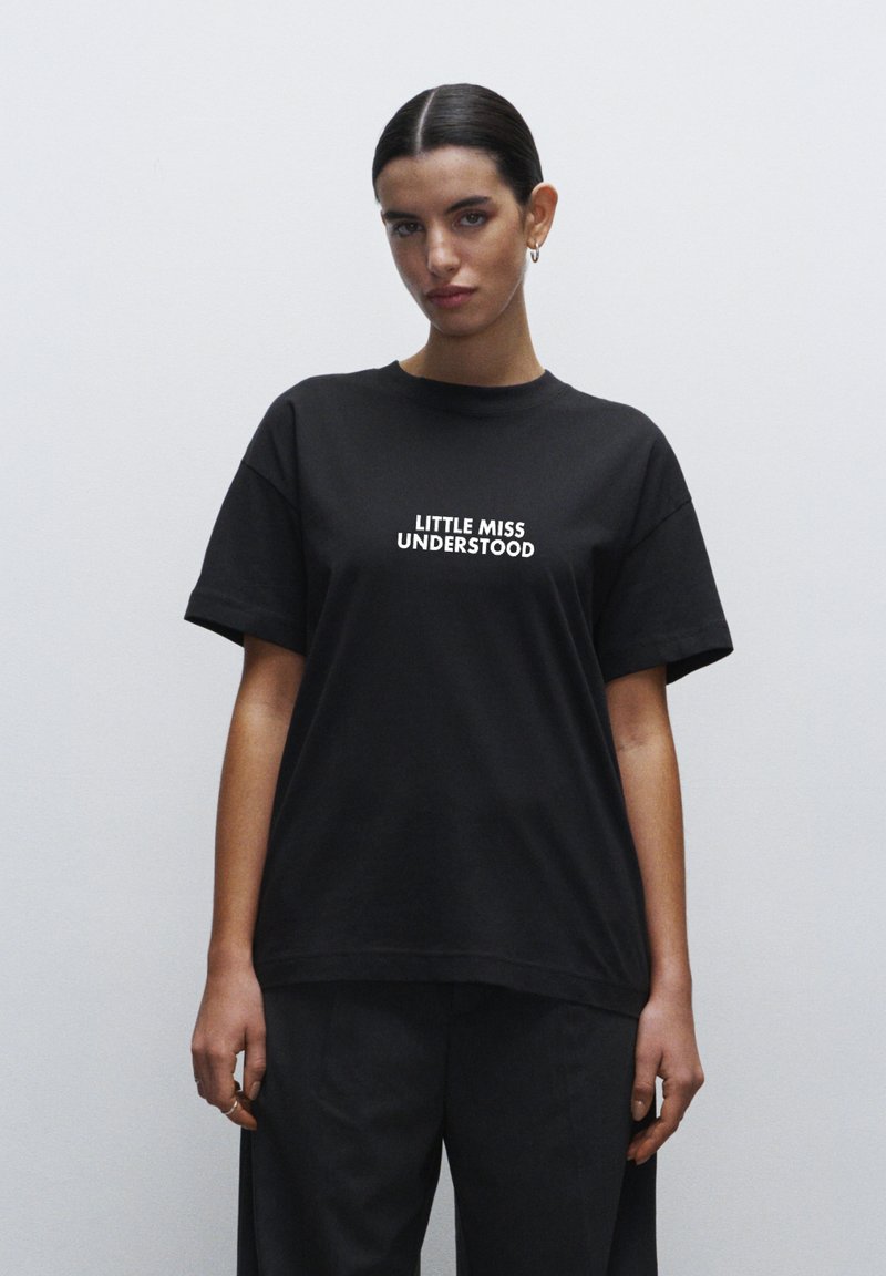 T-shirt di cotone nera a maniche corte e vestibilità comoda, con scritta bianca "LITTLE MISS UNDERSTOOD" sul petto.
