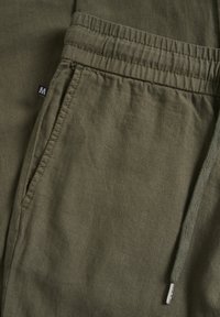Pantaloni jogger in lino verde oliva con cintura elastica, tasche laterali e chiusura con lacci dotati di punta in metallo argentato.