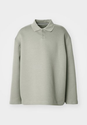 Polo verde cu mâneci lungi, realizat dintr-un material moale. Prezintă un guler, o închidere cu trei nasturi și o croială lejeră cu manșete ribbate.