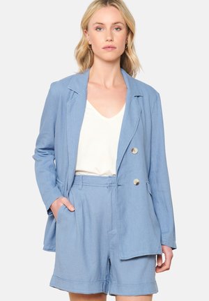 Světle modrý lněný blazer se dvěma knoflíky, klopami a postranními kapsami, doplněný o odpovídající kraťasy, vytváří sladěný outfit.