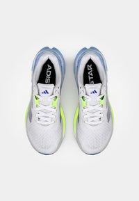 Baskets blanches en matériau en maille, avec des accents jaune-vert vif et une semelle bleu clair. Présentent des lacets et un logo de la marque sur la languette.