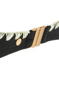 Cintura intrecciata nera con dettagli in frange bianco sporco e una chiusura in metallo dorato con meccanismo di chiusura doppio. Accentuata da un logo metallico.