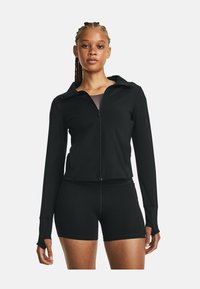 Schwarze Sportjacke mit Reißverschluss, langen Ärmeln und Daumenlöchern, kombiniert mit schwarzen figurbetonten Shorts. Glatter, dehnbarer Stoff.