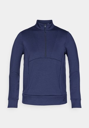 Jersey de cremallera en el cuello de color azul marino, con mangas largas, tejido texturizado, diseño ajustado y una costura distintiva que atraviesa el pecho y los hombros.