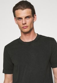 Zwarte t-shirt met korte mouwen en een ronde hals, met een zachte, gladde textuur en minimale stikdetails.