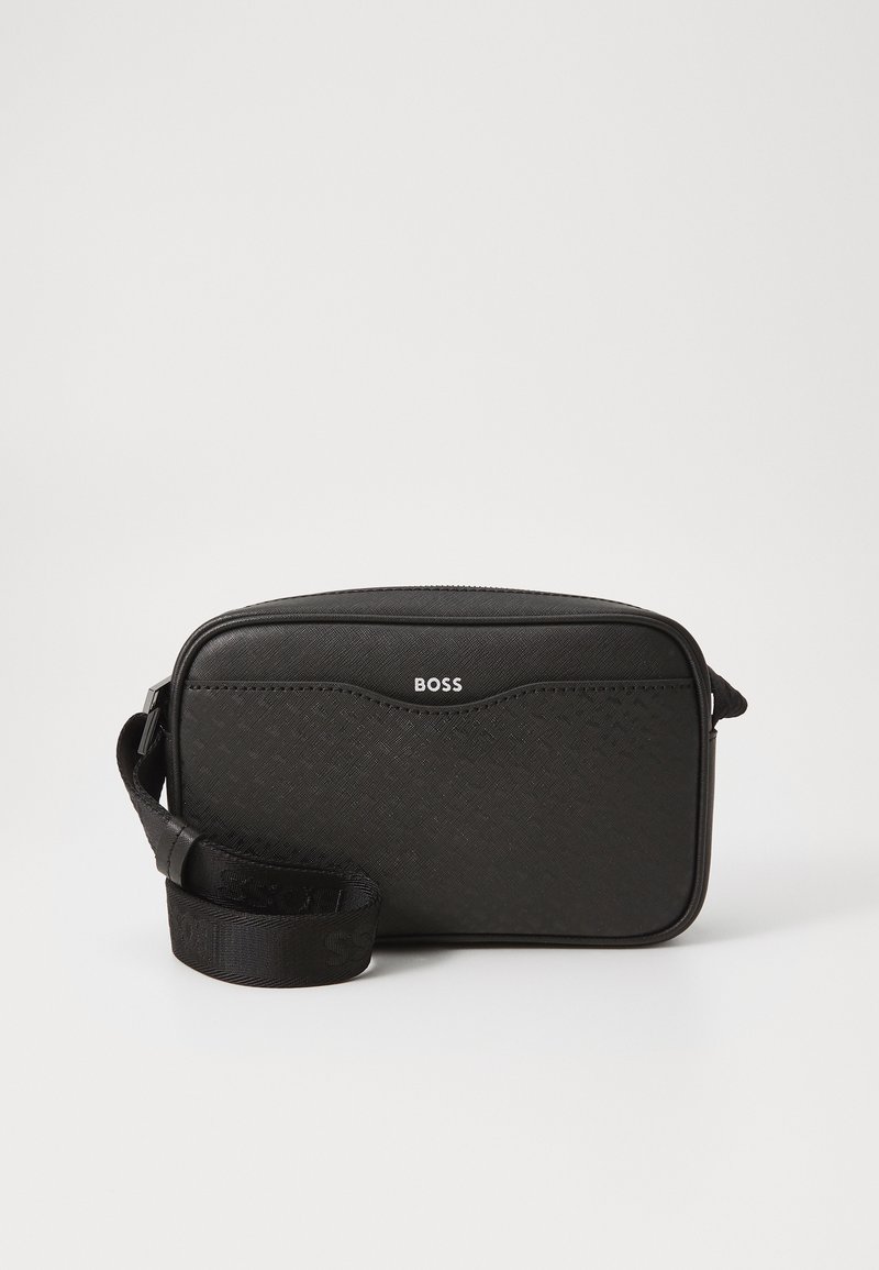 Black crossbody bag with textured material, rectangular shape, zip closure, and an adjustable strap. Features a subtle logo on the front.