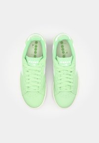 Sneaker in suede verde con dettagli bianchi, caratterizzati da una punta rotonda, lacci piatti e una colla imbottita. L'interno presenta una soletta con motivo.