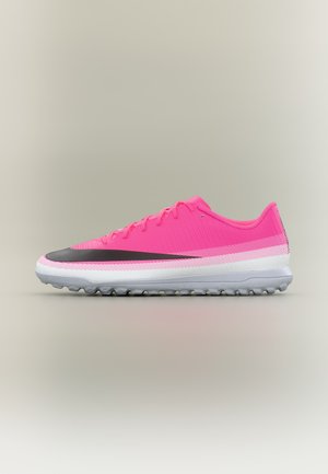 Hellpinkfarbener Sportschuh mit schwarzem Swoosh, weißer Zwischensohle und grauer strukturierter Sohle, seitlich auf neutralem Hintergrund gezeigt.