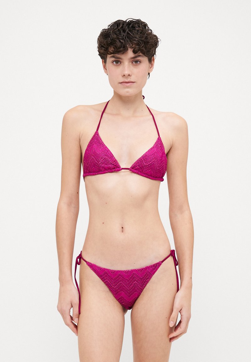 Fuchsia bikini with a triangular top and zigzag texture. Features thin ties at the neck and adjustable side ties on the bikini bottom.