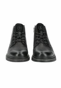 Botas de tobillo de cuero negro con un acabado suave, con diseño de cordones, tacón bajo y cremallera lateral. Suela de goma con un ligero detalle de dibujo.