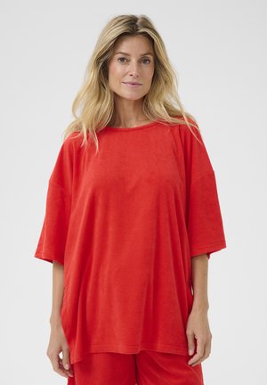 Czerwona, oversized, krótko rękawowa bluzka z miękkiego materiału. Ma okrągły dekolt i luźny krój, połączona z pasującymi spodniami.