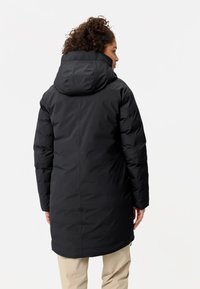 Cappotto imbottito lungo e nero con cappuccio, dotato di polsini elastici e taglio dritto. Tessuto liscio e design minimalista. Vista posteriore.