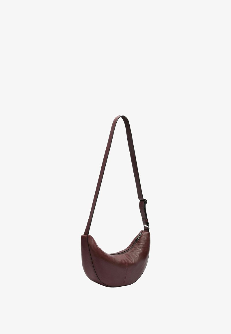 Bordowa skórzana torba na ramię o zaokrąglonym kształcie, zamykana na zamek błyskawiczny, z regulowanym paskiem. Gładka faktura i jednolity kolor, z minimalną ilością metalowych elementów.