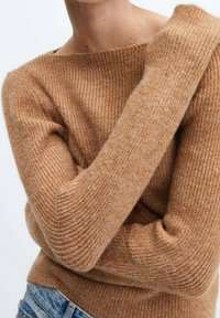 Brązowy sweter prążkowany z szerokim dekoltem i długimi rękawami, wykonany z miękkiego, teksturowanego materiału, w zestawie z niebieskimi dżinsami.