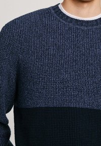 Stickad tröja med en strukturerad design i marinblå och mörkblå horisontella ränder. Rund halsringning, synliga sömmönster.