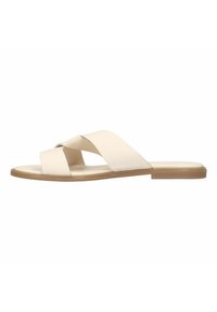 Beige flat sandals with cross-strap design, made of smooth material, featuring a minimalistic shape and a tan rubber sole.