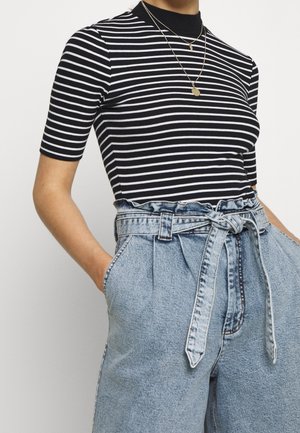 Zwart-wit gestreepte korte mouwen top, gecombineerd met hoge taille, lichtblauwe spijkerbroek, met een knoopriemdetail.