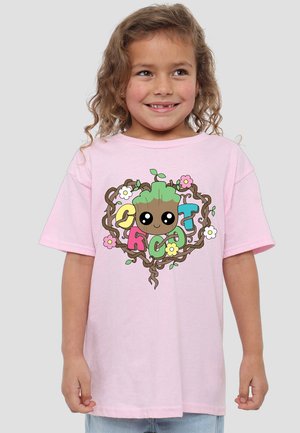 Light pink cotton t-shirt featuring a cartoon character surrounded by flowers and vines. Short sleeves and relaxed fit design.
