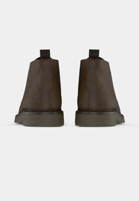 Rudi odos kulkšnies batai su tekstūruotu žaliu padu, turintys traukimo kilpą gale ir vientisą šoninių siūlių dizainą.