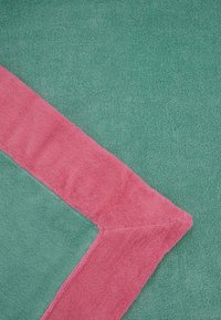 Asciugamano da bagno turchese con un bordo rosa a contrasto. Texture morbida, con una finitura soffice e assorbente e angoli puliti e angolari.