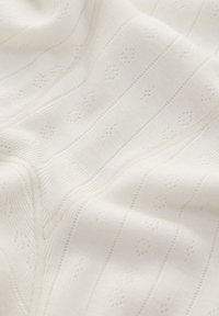 Tejido blanco de punto con patrones florales sutiles y rayas horizontales, con una textura suave y un ligero brillo.