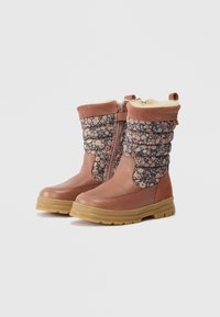 Botas de inverno castanhas com tecido acolchoado floral, fecho lateral, forro em lã e solas de borracha expostas sobre um fundo branco simples.