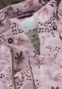 Lichte roze jas met bloemenpatroon, voorzien van een ritssluiting, knoopaccenten en een zichtbaar etiket van ademend materiaal aan de binnenkant.